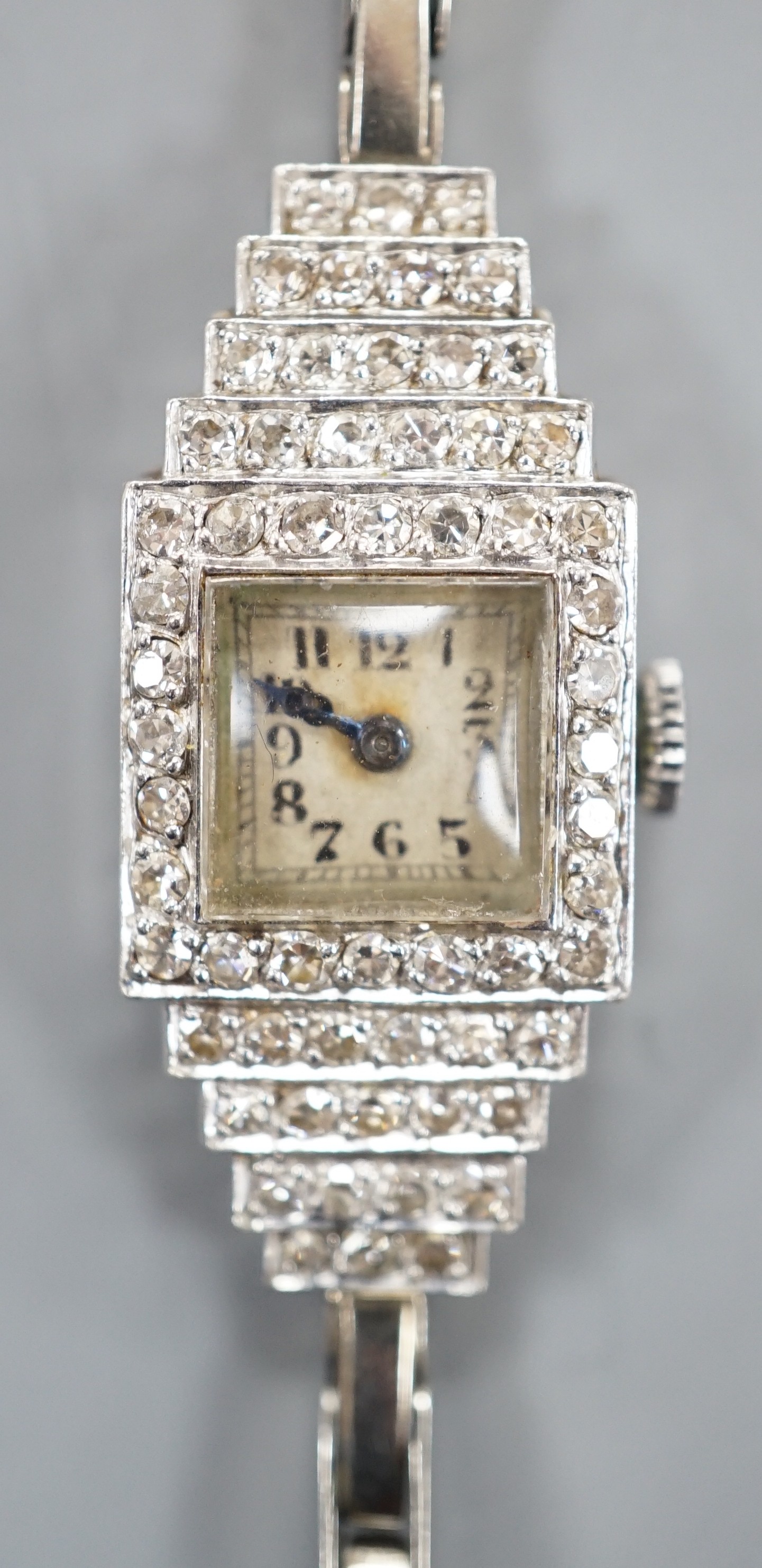 A lady's mid 20th century white metal (stamped platinum) and diamond cluster set Vertex cocktail watch, with stepped lugs, on a 9ct white metal expanding bracelet, 15.5cm, gross weight 15.6 grams.